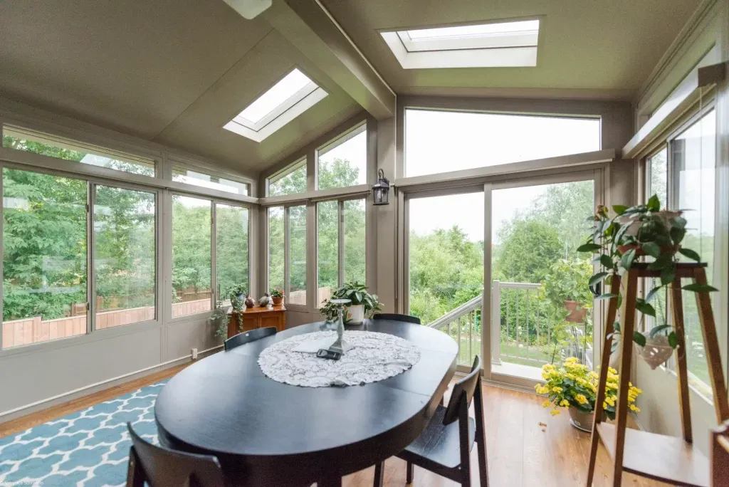 3 season glass room interior with vaulted skylights dark dining table and wood flooring