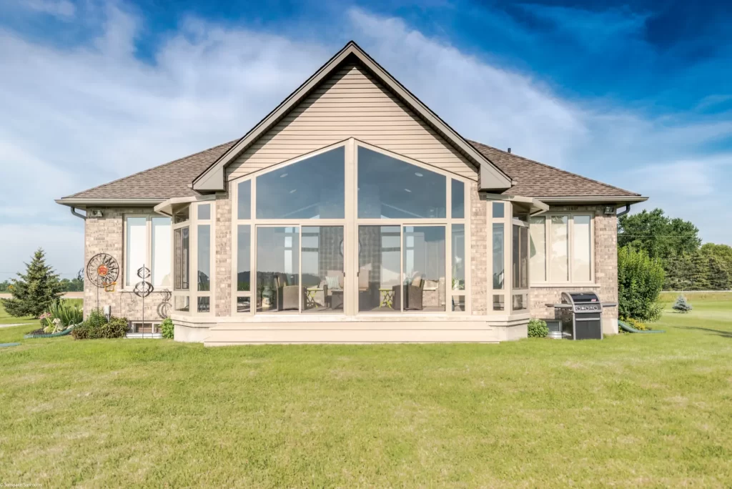 Sunspace Model 400 gabled sunroom addition with large glass windows on a brick house