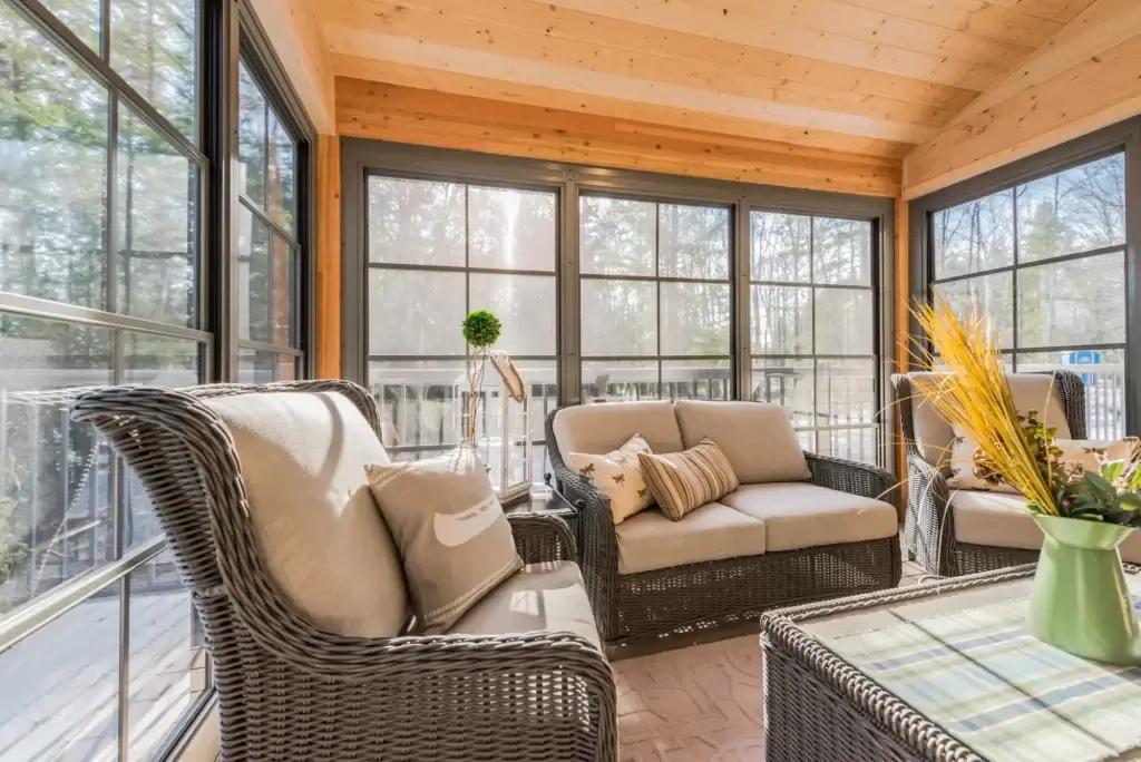 Cozy sunroom with Weather Master windows featuring wicker seating and scenic wooded backyard views