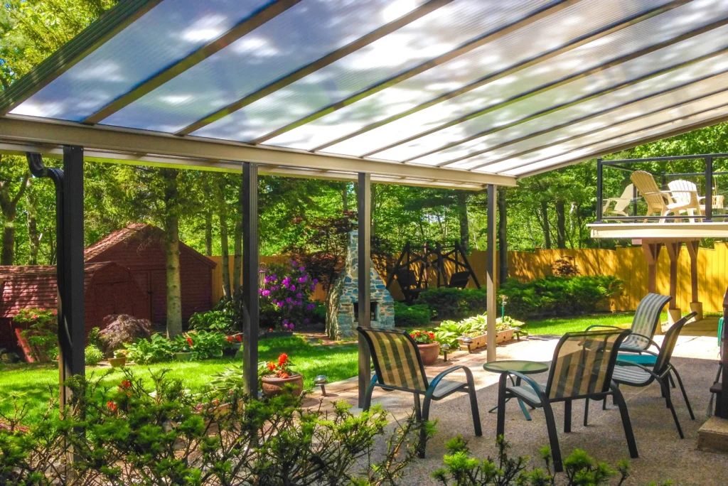 Translucent acrylic patio covers installed over an outdoor seating area with scenic backyard greenery