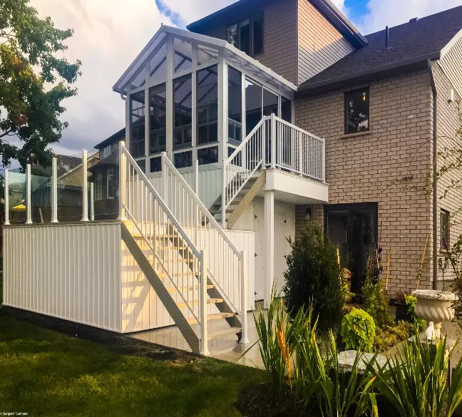 White picket and glass railing system installed on a raised deck with access stairs attached to a sunroom
