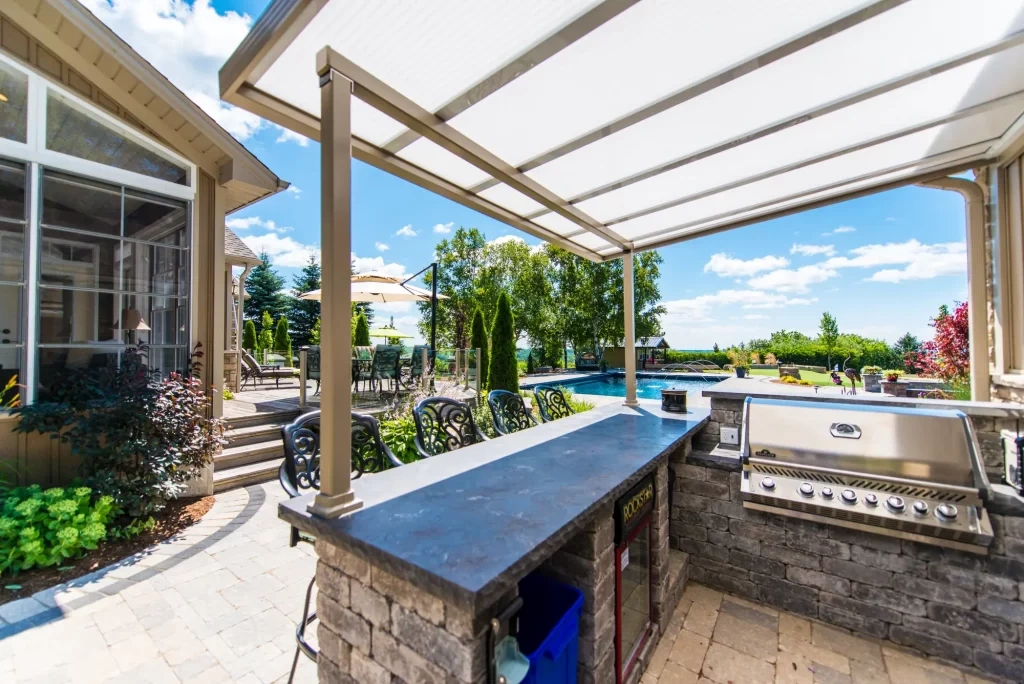 Hunt Home outdoor kitchen patio cover with translucent roof over stone bar grill