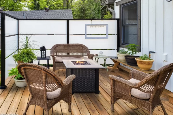 Sunspace SunWall privacy screen installed on a wooden deck around wicker chairs and fire pit