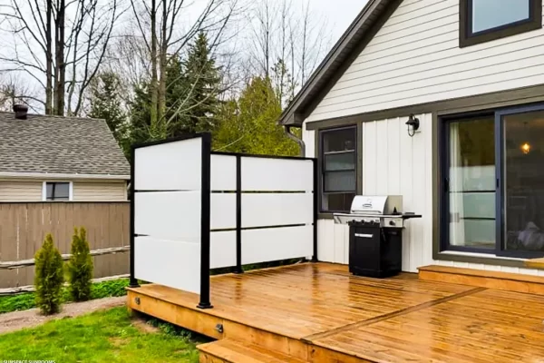 Black Sunspace privacy wall with white panels installed on a wooden deck near grill