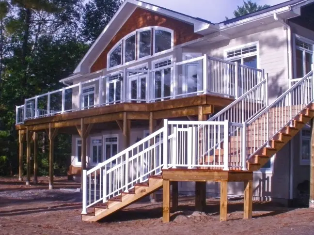 White glass deck railing and picket stair railing on an elevated wooden deck