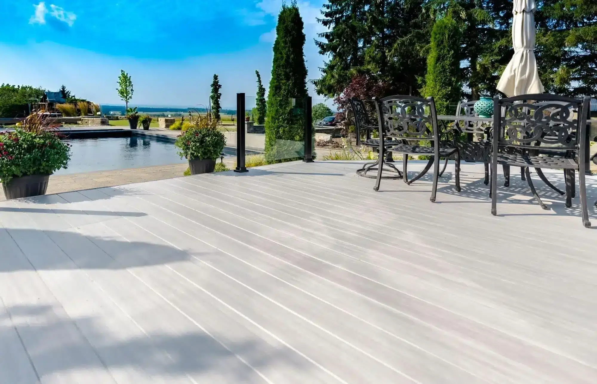 Light grey aluminium decking system with glass railings patio dining set and swimming pool view