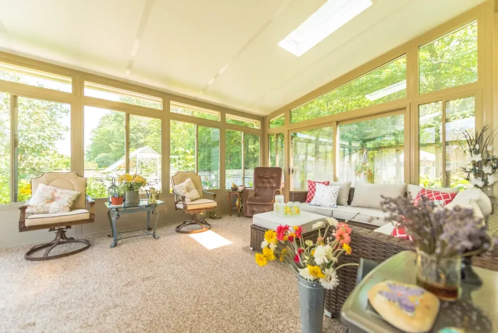 Bright glass sunroom interior with tan framing skylight carpet and lounge furniture