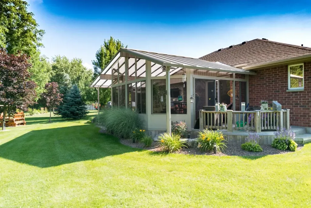 Sunspace glass sunroom addition with sloped roof on a brick home deck